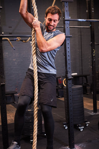 Man climbing rope in gym